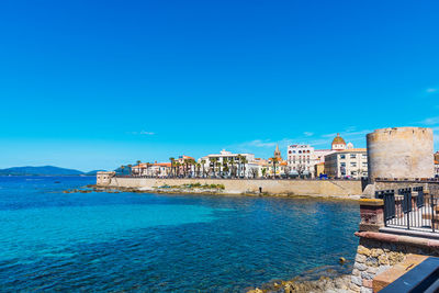 Scenic view of sea by buildings against clear blue sky