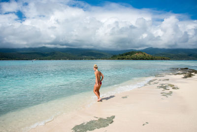 Full length of shirtless man on beach against sky