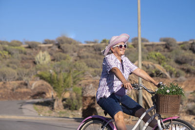 Smiling senior woman driving bicycle outdoors