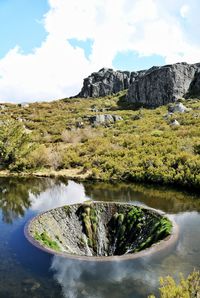 Scenic view of a pit in a lagoon amidst mountains against the sky, in serra da estrela, portugal.