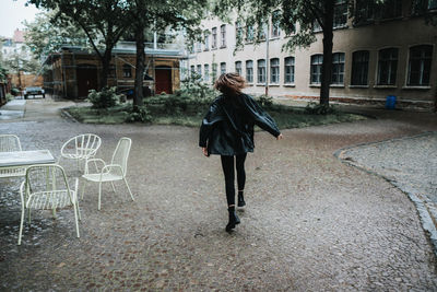 Rear view full length of young woman on walkway in city