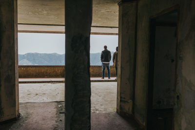 Rear view of man and woman standing at abandoned building