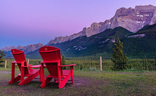 Red chairs on landscape against clear sky