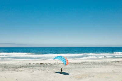 Young man paragliding on beach of paciifc coast in baja, mexico.