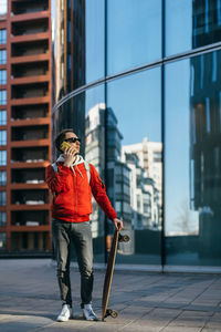 Hipster in sunglasses hold in hand longboard and talking on mobile phone. selective focus on male. 