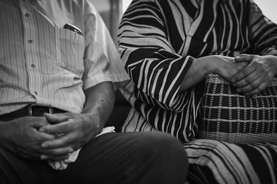 Midsection of man and woman sitting indoors