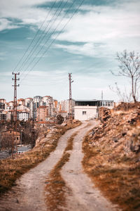 Road amidst buildings in city against sky