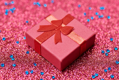 Red gift box on festive glitter. little closed box with bow and gift. surprise giftbox for loved one