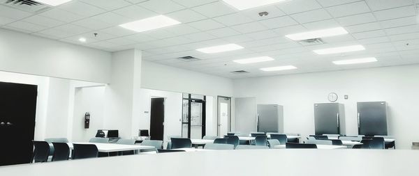 Empty chairs and tables in illuminated room