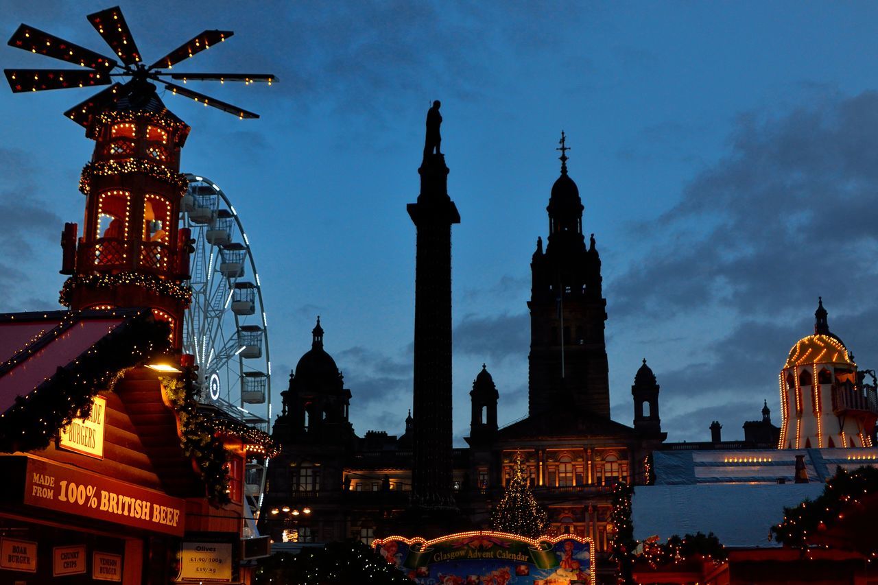 LOW ANGLE VIEW OF ILLUMINATED BUILDINGS AT DUSK