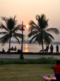 People at beach against sky during sunset