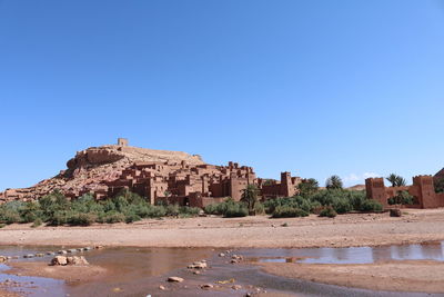Castle by buildings against clear blue sky