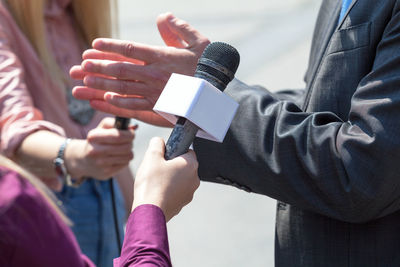 Cropped image of reporters taking interview of man