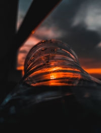 Close-up of glass against orange sky