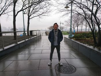 Full length portrait of young woman standing on footpath