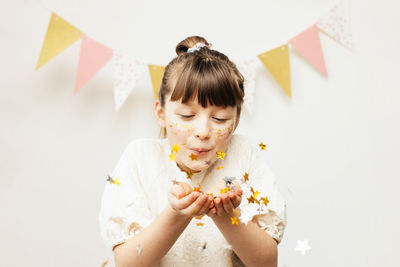 Adorable little girl blows glitter off her hands. holiday, birthday, party for kids. happy childhood