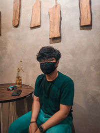 Man wearing sunglasses standing against wall