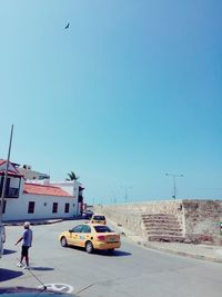 Rear view of man walking by car on road