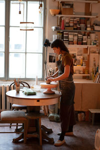 Young female potter maker work with clay on pottery wheel in creative space or professional studio