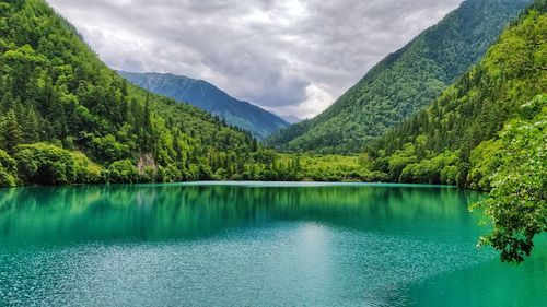 Scenic view of lake by mountains against sky