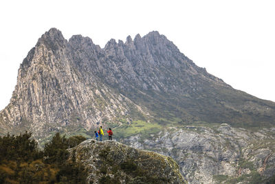 People standing on rocky mountain against sky