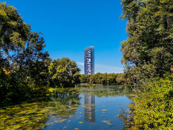 Scenic view of lake by buildings against clear blue sky