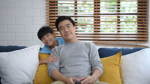 Rear view of father and son sitting on floor