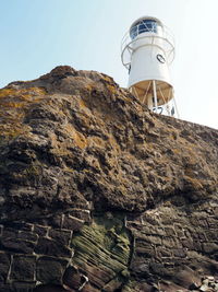 Low angle view of lighthouse by buildings against sky