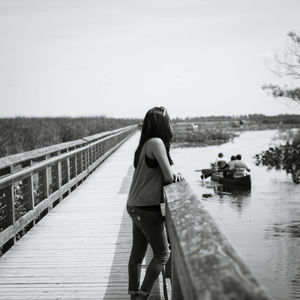 Rear view of woman standing on lake against clear sky