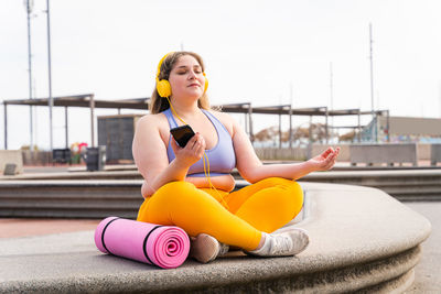 Young woman with smart phone doing yoga