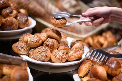 Close-up of hand holding meat in plate on table