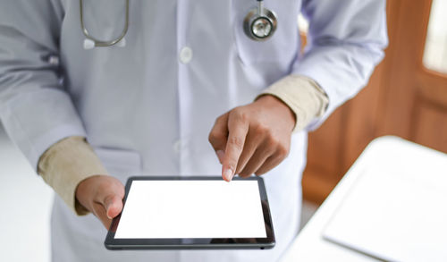 Midsection of man holding smart phone on table
