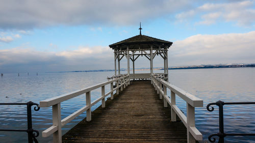 Gazebo over sea against cloudy sky