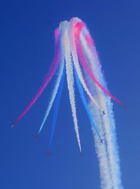 Low angle view of airshow against clear blue sky