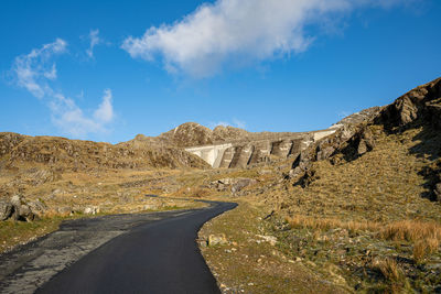 Road amidst mountains against blue sky