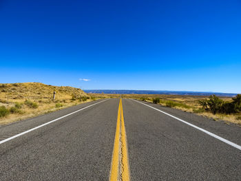 Empty road against clear blue sky