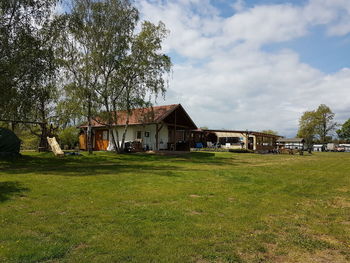 Houses and trees on field against sky