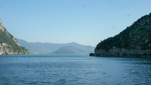 Scenic view of sea and mountains against clear blue sky