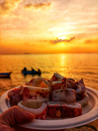 Meat in container on beach against sky during sunset