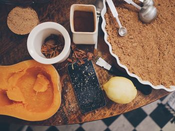 High angle view of mobile phone with spices and pie on table