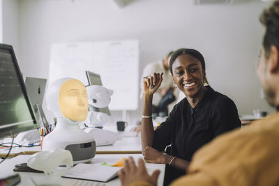 Smiling female phd student discussing with man at desk in innovation lab