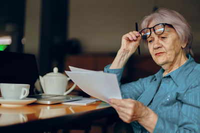 Senior woman doing paper work at cafe