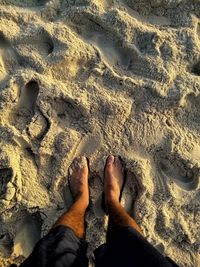 Low section of man standing on sand at beach