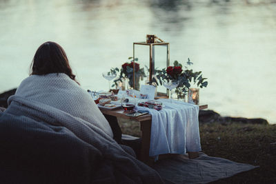 Rear view of woman sitting by lake