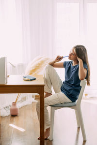 A high school student sits at home at her desk, takes a break before preparing for classes or exams