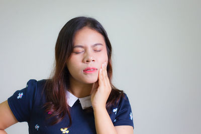 Young woman suffering from pain against white background