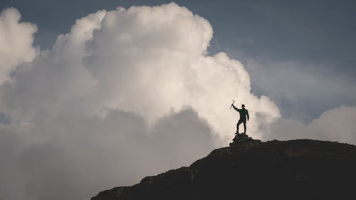 Low angle view of silhouette man standing on mountain against sky