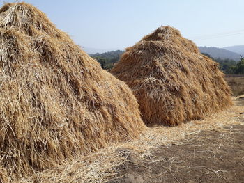 Hay bales on field against clear sky