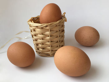 Close-up of eggs in basket on table against white background