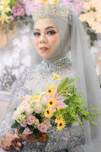 Portrait of young woman holding flower bouquet